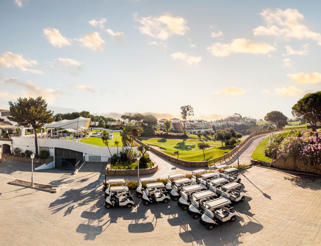 Golfanlage La Cala Golf mit Clubhouse, Golfplätzen und Golfhotel, im Vordergrund mehrere Buggies