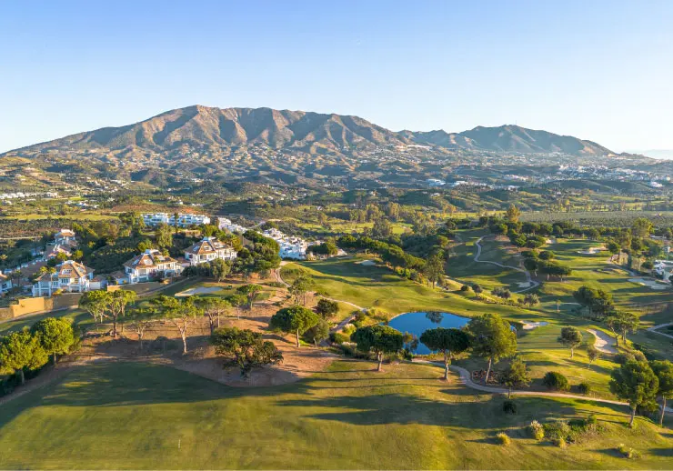 Panorama des La Cala Golf mit Golfplätzen und Häusern, Gebirge im Hintergrund