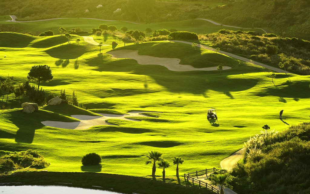Ansicht eines Golfplatzes mit mehreren Bunkern, daneben führen Wege vorbei