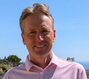 Foto von Murdo McCorquodale: lächelnder Mann, im Hintergrund Bäume, Meer und blauer Himmel