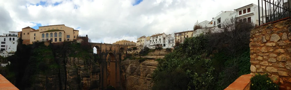Panorama der Steinbogenbrücke in Ronda mit einer Reihe von Häusern auf dem Felsen