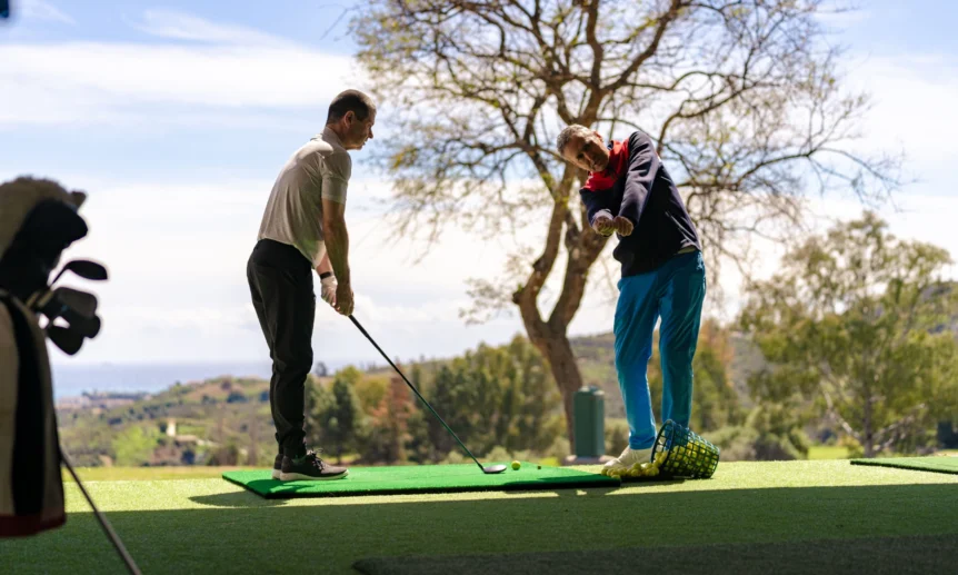 Golflehrer bringt einem Golfer den richtigen Abschlag bei.