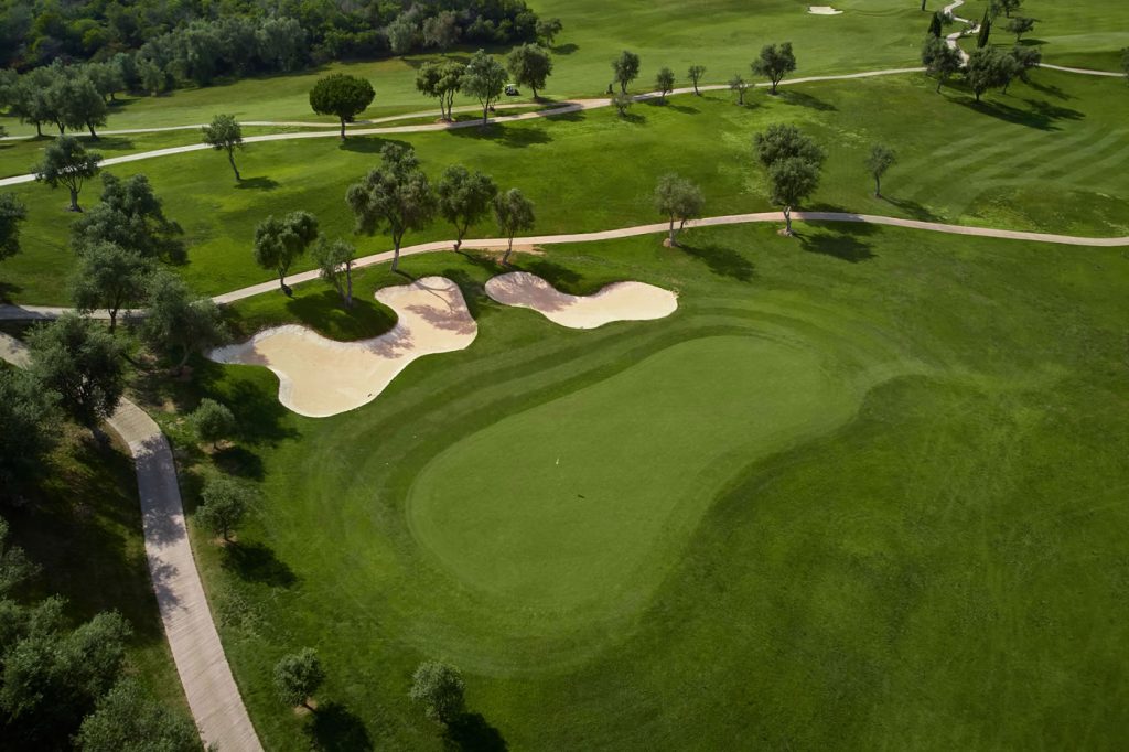 Blick von oben auf einen Golfplatz mit zwei Bunkern im Marbella Golf & Country Club, im Hintergrund verlaufen zwei schmale Wege