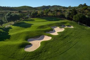 Blick von oben auf einen Golfplatz des Marbella Golf & Country Clubs mit 3 Bunkern, hügelige Landschaft im Hintergrund